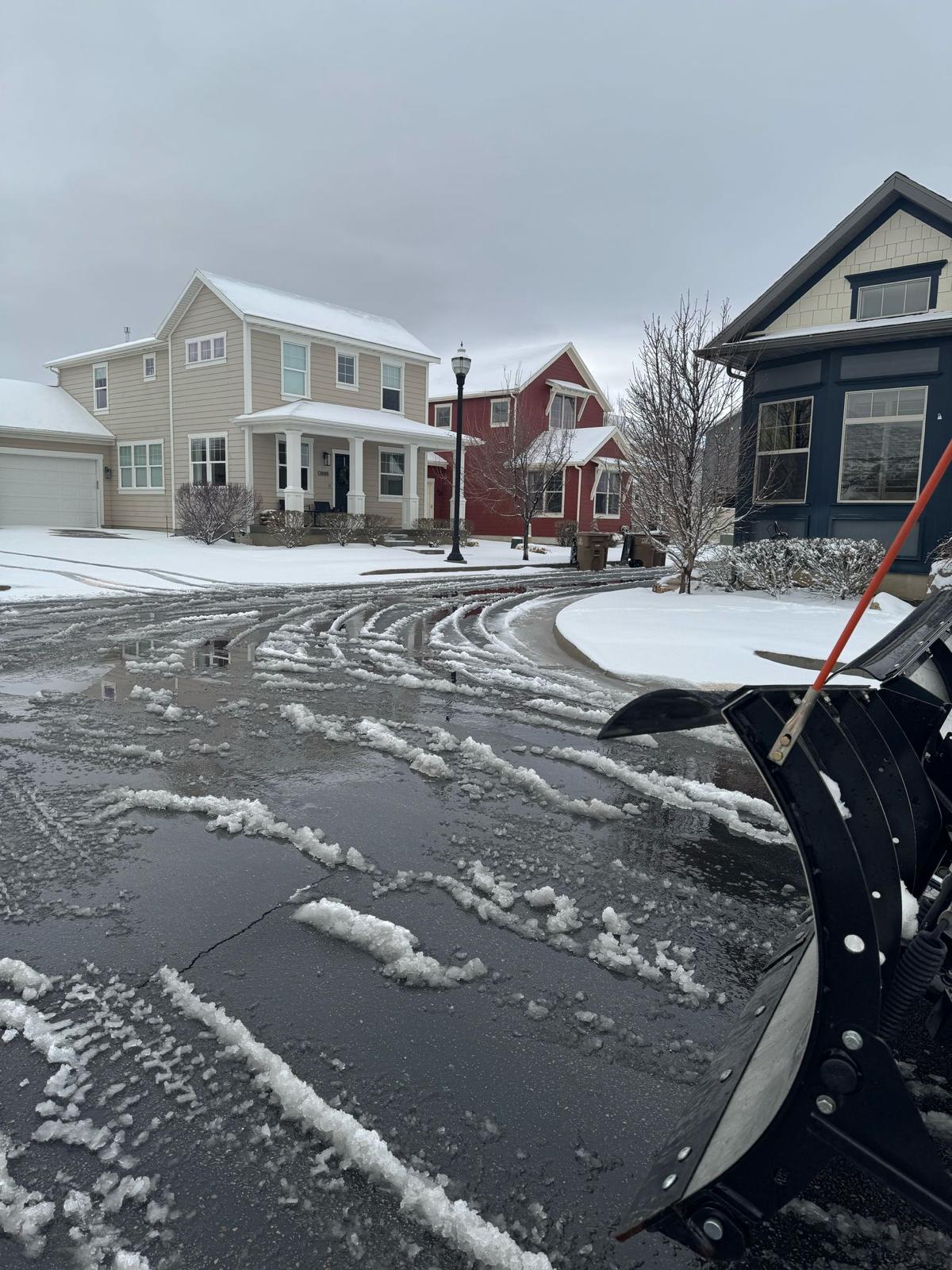 Plow truck clearing residential driveway after snowstorm