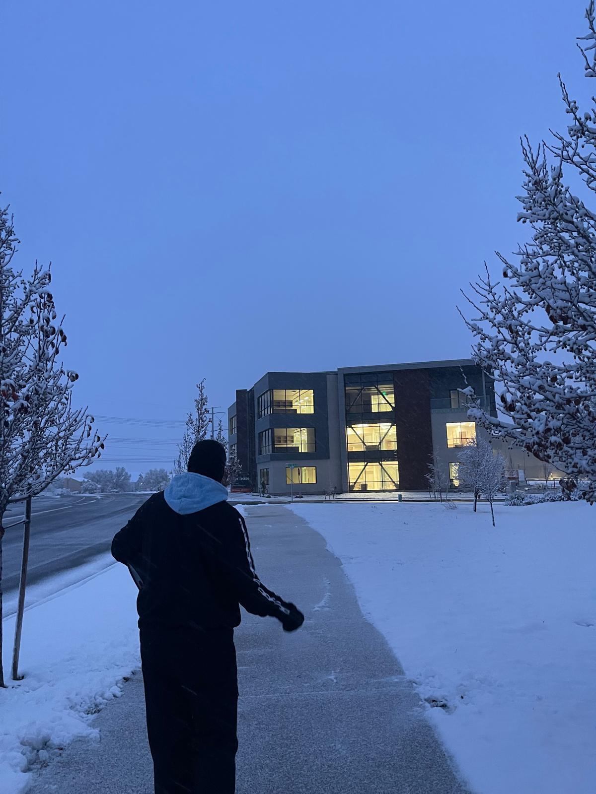 Team member walking to lit office building during snow event