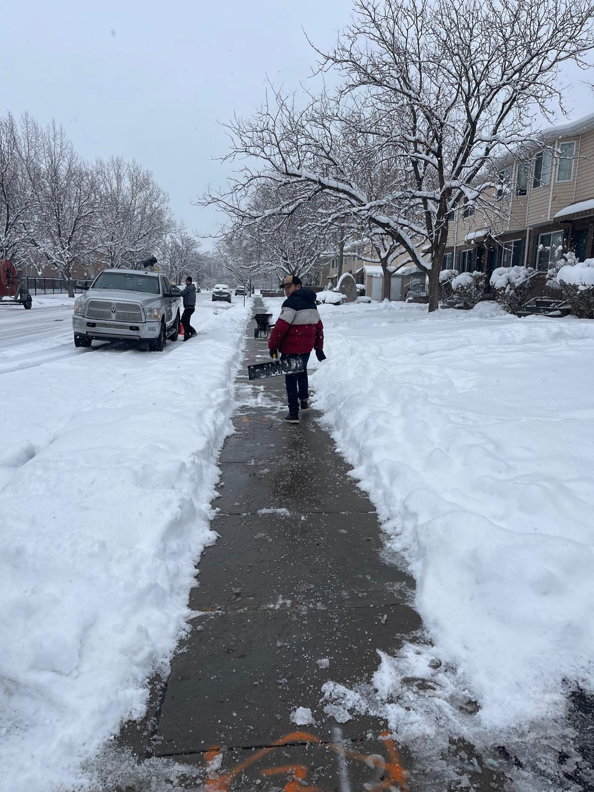 Crew clearing residential sidewalk after heavy snow