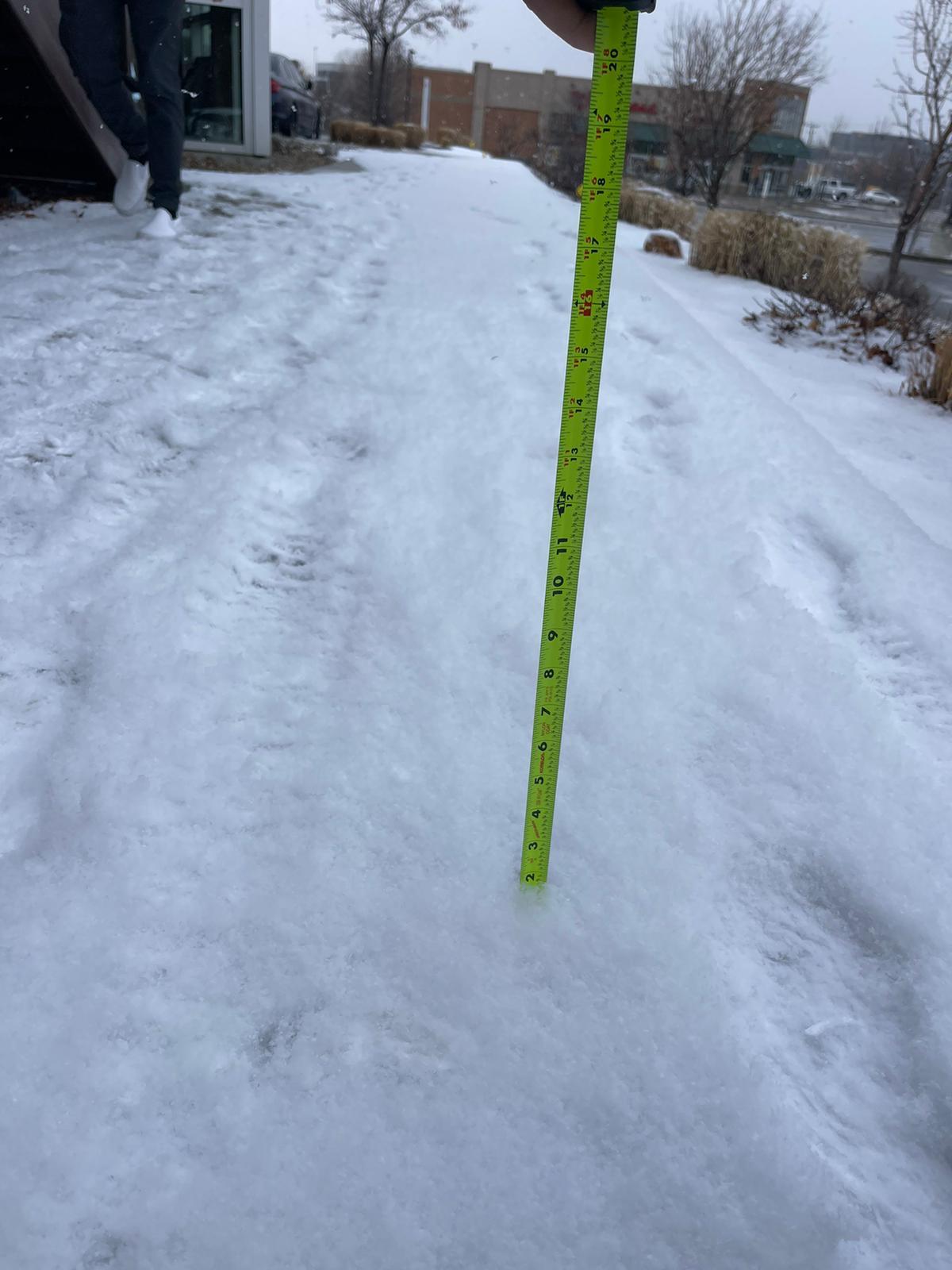 Tape measure documenting snow depth on sidewalk